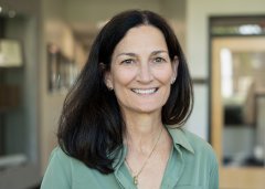 Sharon Wise, with shoulder-length hair and waering a green top, smiles at the camera.