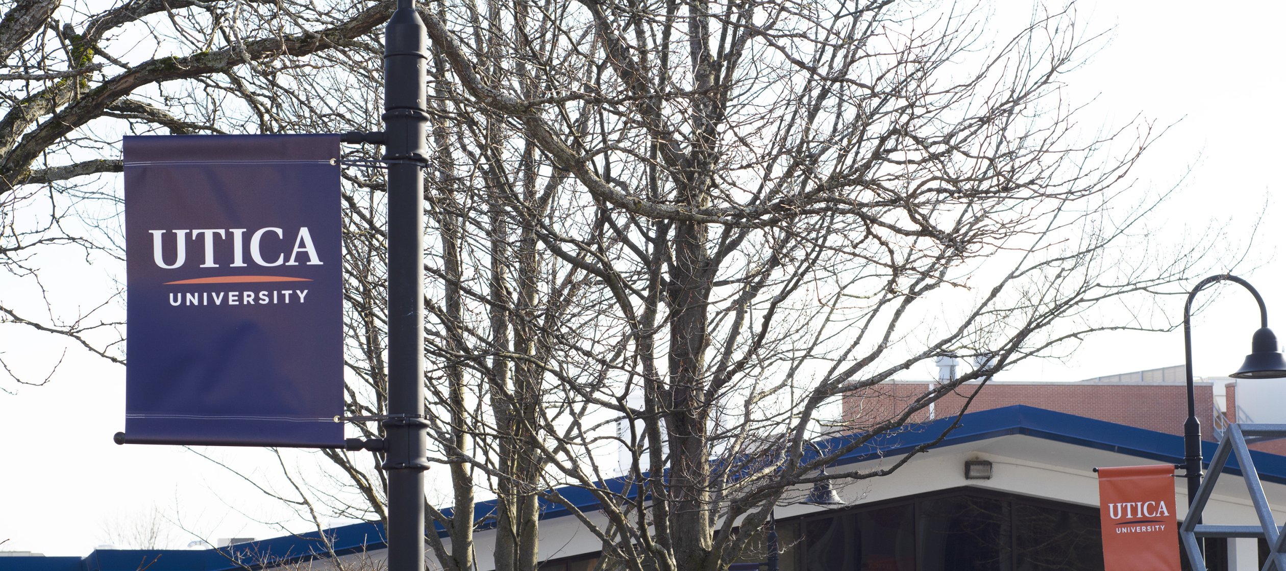 Blue and orange Utica University banners hang outside Gordon Science Center.