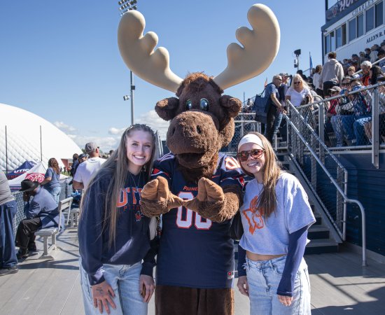 Students stand next to Trax near the bleachers of Gaetano Stadium.