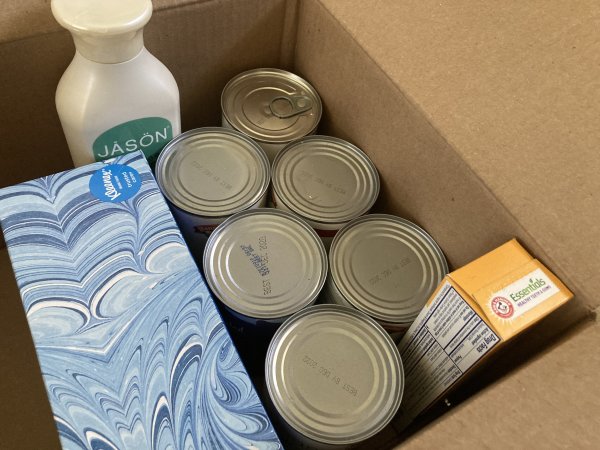 Canned goods and hygiene priducts in a cardboard box.